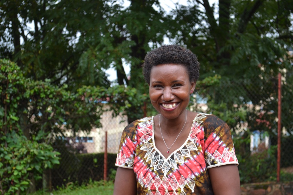 Woman smiling wearing a colorful traditional dress.